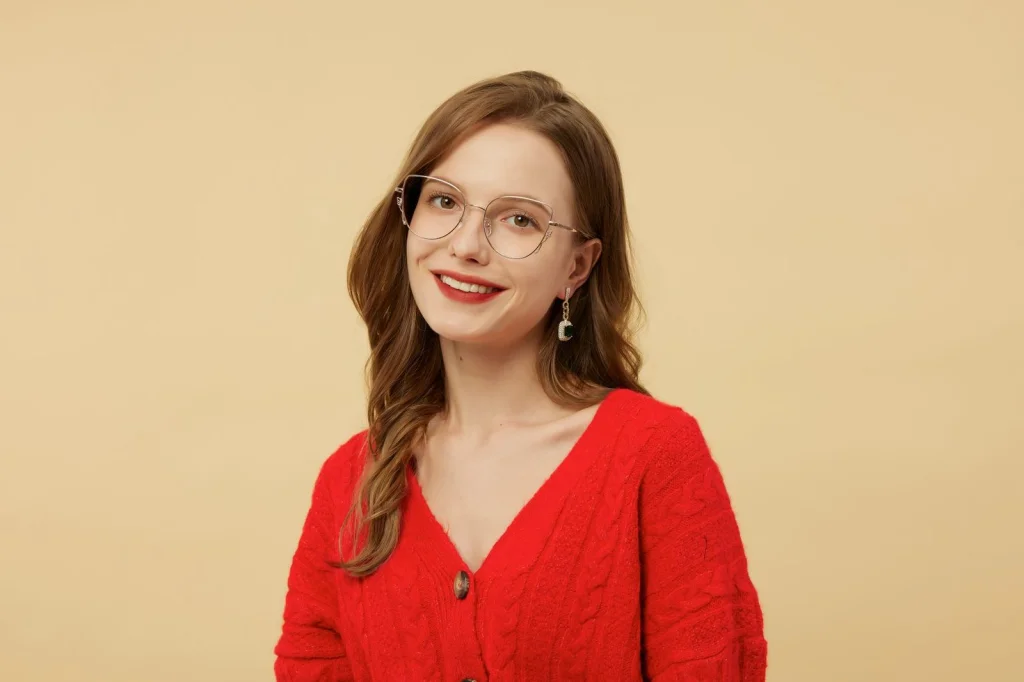 Professional woman in her 30s wearing thin-framed glasses, neutral expression, navy blue blazer, against plain gray background, soft even lighting from front, passport photo style, high resolution