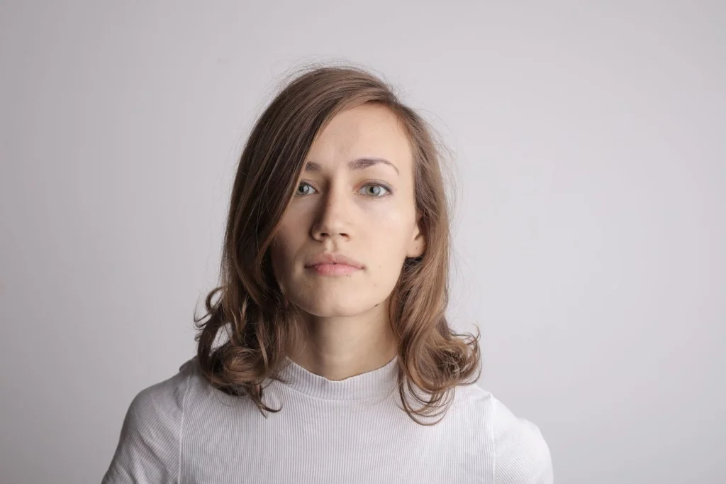 Before and after comparison of a professional headshot: original photo with cluttered office background transformed to clean gray studio background, same person in business attire, dramatic improvement in professional appearance