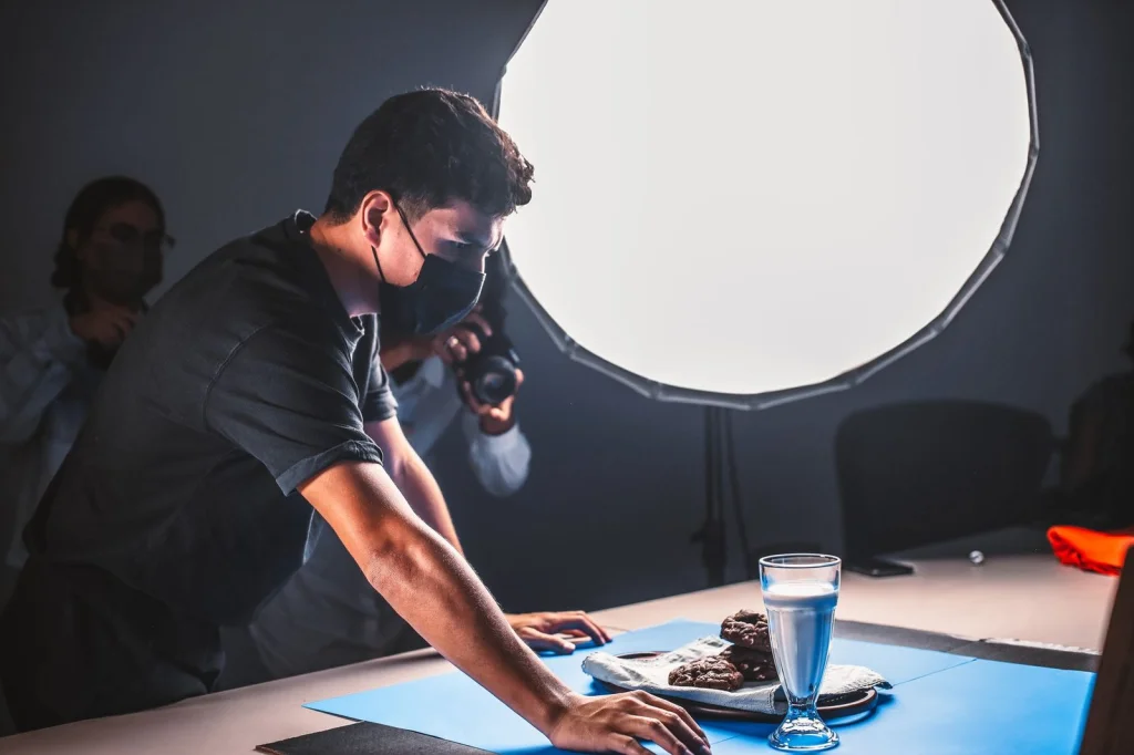 Professional product photographer removing backgrounds from jewelry photos using AI software, concentrated expression while fine-tuning edge selection on a high-resolution monitor, sitting at a clean studio desk with color-calibrated displays, soft north-facing window light, eye-level medium shot, commercial photography workspace