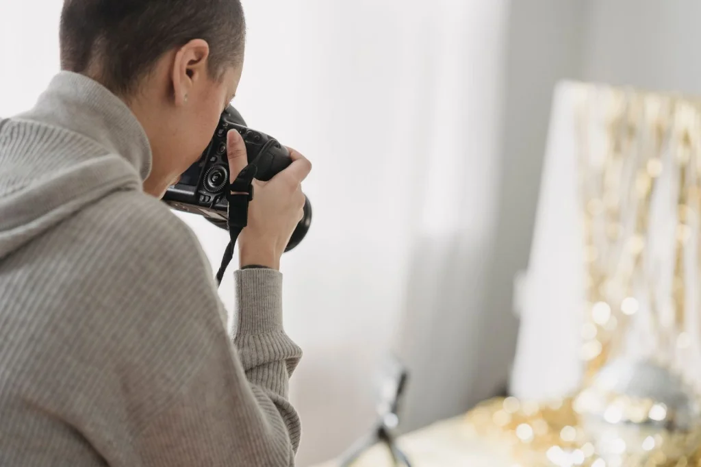Professional photographer in their 30s with short black hair, focused expression, sitting at a modern desk with multiple monitors showing before/after background removal comparisons, soft LED desk lighting, eye-level medium shot, editorial workspace photography, shallow depth of field