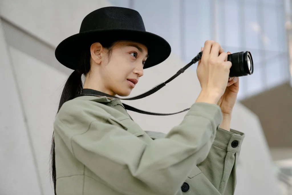 Professional photographer in her 30s with blonde hair in ponytail, setting up white backdrop and softbox lighting for product photography, bright studio space with concrete floors, natural window light mixed with studio lights, wide shot showing full setup, commercial photography behind-the-scenes