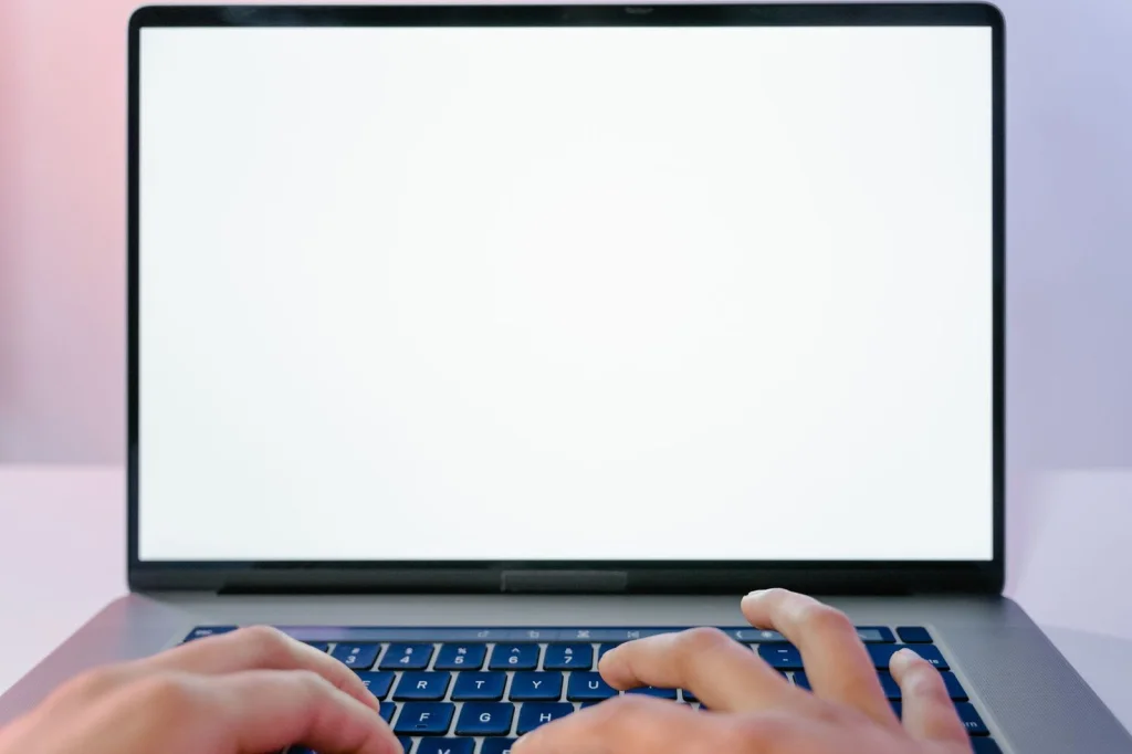 Computer screen showing Canva interface with background removal tool active, before and after images side by side, modern office desk setup with keyboard and mouse, soft daylight from window, slightly angled medium shot, professional web design aesthetic