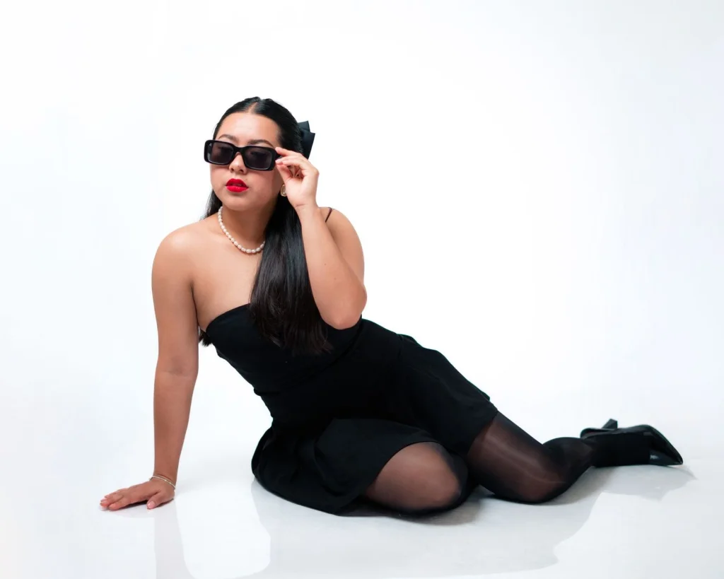 Fashion influencer in her 20s with sleek black bob hair, wearing white minimalist blazer, neutral expression, clean beige background, soft diffused lighting from left, waist-up portrait, lifestyle commercial photography, f/4 depth