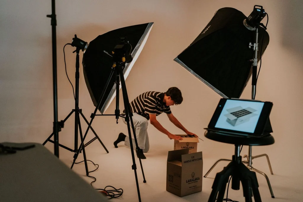 E-commerce product photography setup with white backdrop, multiple fashion items laid out on a clean table, ring light and camera on tripod, bright studio lighting, overhead flat-lay perspective, commercial product photography