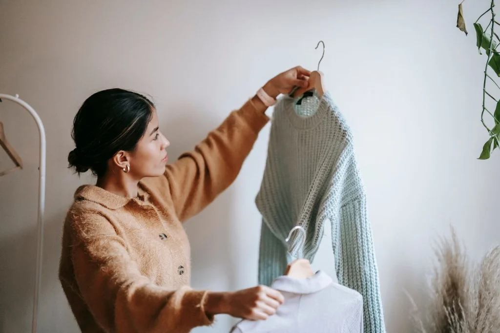 Young woman in her 20s with dark hair comparing two photos on a modern laptop screen, one blurry and one crystal clear, sitting at a white desk with notebooks, soft natural light from window, medium shot at eye level, lifestyle photography, shallow depth of field