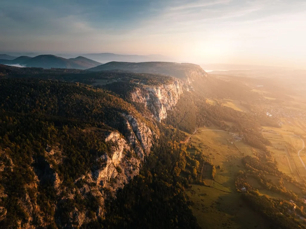 Side-by-side before and after showing a mountain landscape with a lake, original still photo transforming into animated version with gentle water ripples and moving clouds, golden hour lighting, wide landscape shot, cinematic nature photography
