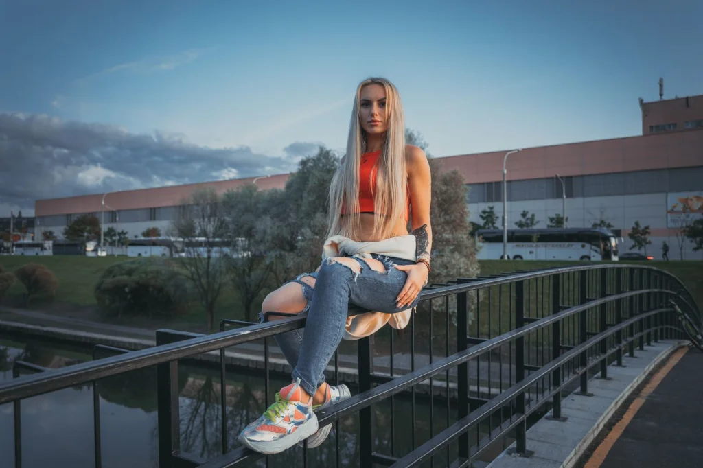 Young woman with long blonde hair, denim jacket, happy expression, standing in a field of sunflowers, golden hour sunlight, three-quarter view from waist up, lifestyle photography, warm color grading, shallow focus